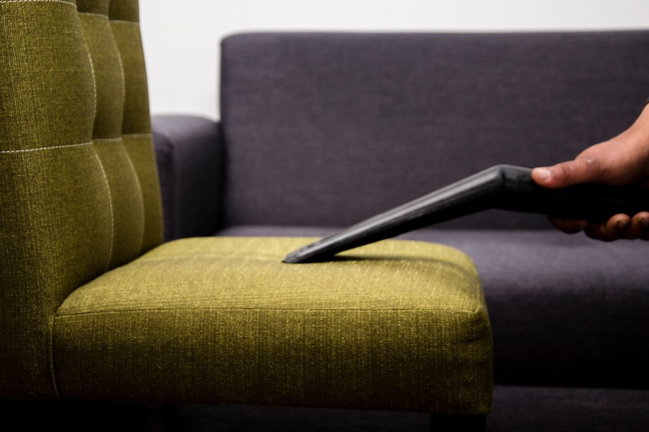 Mastering the First Impression: Your intriguing post title goes here Close-up of a person vacuuming a modern sofa chair indoors, highlighting cleaning service.